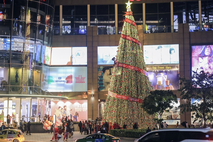 A giant Christmas tree stands outside a shopping mall.