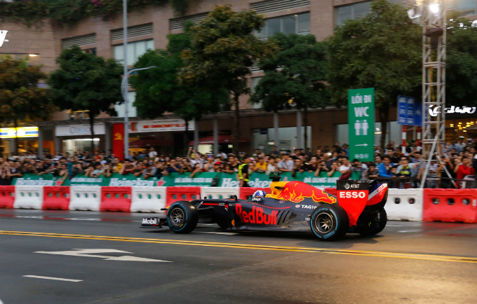 A crowd is seen waiting for the F1 racing car. The car has been lifted to adapt to the street condition in Vietnam.