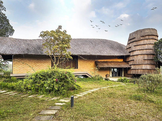 The elevated floor helps homeowners avoid humidity and termite. Starcase is hidden inside construction evoking a rice straw stack. Meanwhile, thatched roof creates shadow, sound-proof and control solar radiation efficiently.