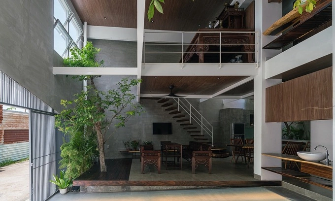 The parking lot, living room, dining room, kitchen, toilet, and one bedroom are on the first floor. Trees are planted in many spaces, while the brown shades of the furniture create a sense of coziness in the house of a three-generation family.