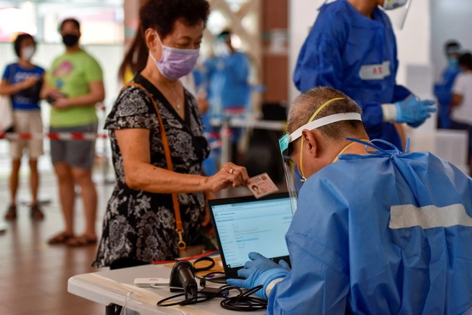 A woman presents her ID card to be tested for the novel coronavirus in Singapore, June 16, 2021. Photo by Reuters