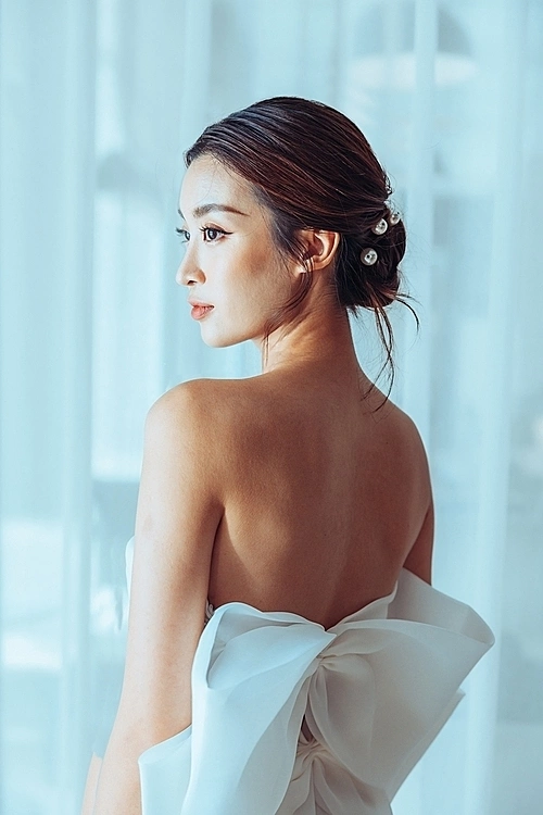 Linh appears in a sweetheart neckline wedding dress design with a large organza bow detail on the back.