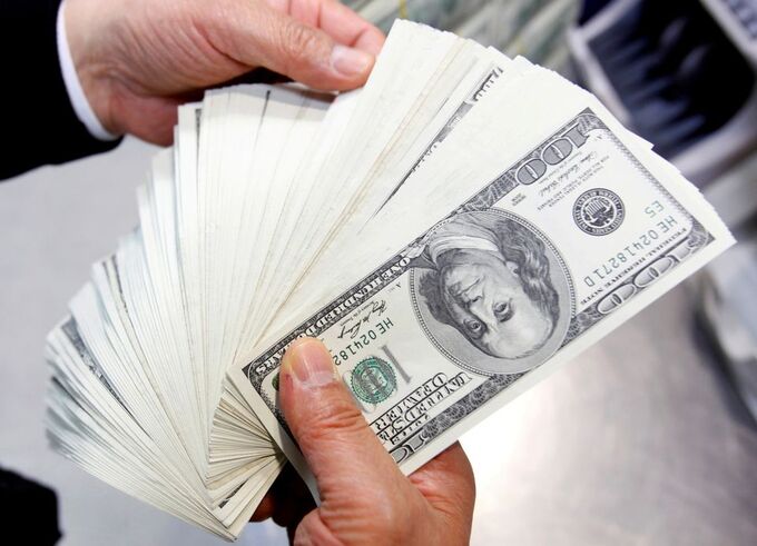 An employee of a bank counts one hundred U.S. dollar notes. Photo by Reuters