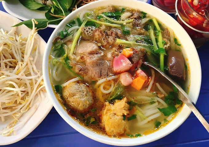 Herbs and bean sprouts are added to Hue-style beef noodle soup. Photo by VnExpress/Ngoc Tran
