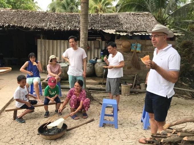 Tourists eat rice paper crackers grilled on the spot in Ben Tre Province. Photo by Quach Duy Thinh