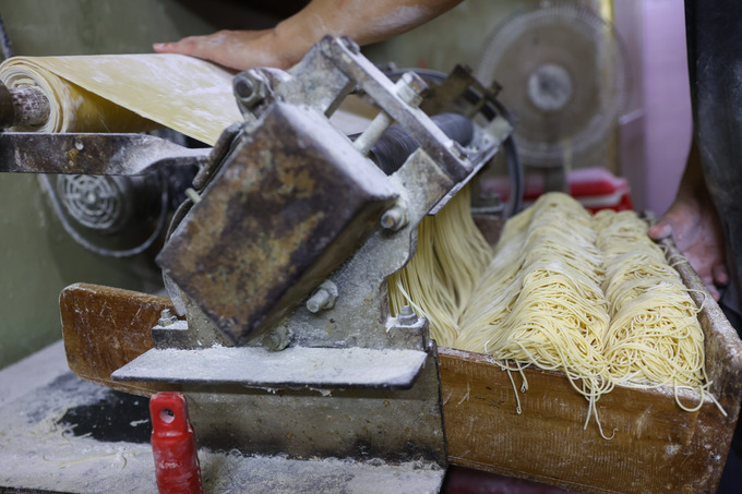 After kneading, the dough is thinned by a roller before being cut into noodles. Photo by VnExpress/Quynh Tran