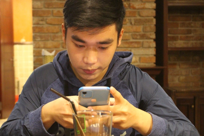 Minh Duc, 21 years old, scrolls through his TikTok feed while having a coffee in April 2023. Photo courtesy of Duc