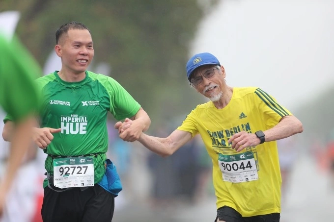 Binh and Trung Hieu, his new friend, hold hands to reach finish line. Photo by Duc Dong