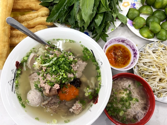 A bowl of pho accompanied by a serving of poached egg in beef blood, fried dough sticks, bean sprouts, and herbs. Photo by VnExpress/Vi Yen.