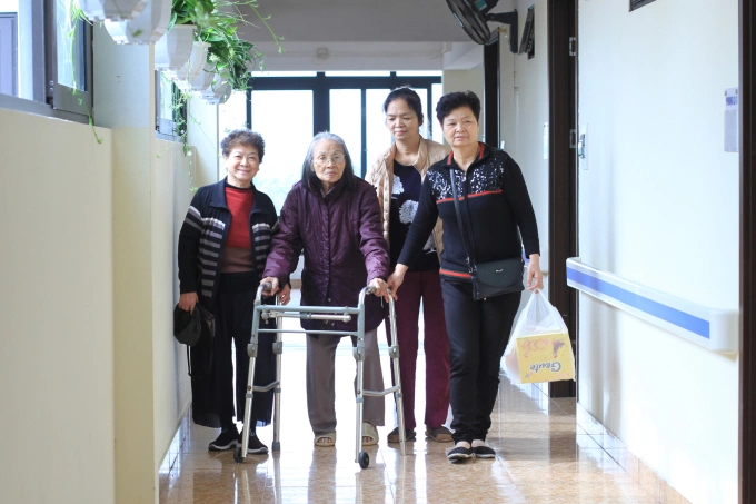Friends of an elderly with physical difficulties, who is living at a nursing home in Thanh Tri District, Hanoi, visit her in the winter of 2021. Photo by VnExpress/Phan Duong