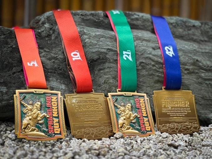 Different band-color goes with the medals for participants in the 5 km, 10 km, 21 km, 42 km race: orange, red, green, and blue. Photo courtesy of VM