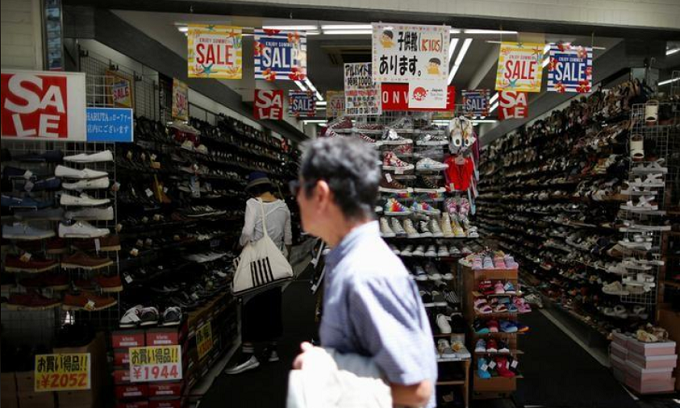 A shopper (L) checks items inside a shoes shop in Tokyo, Japan. Photo by Reuters