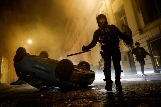 French riot police officers walk next to a vehicle upside down during the fifth day of protests in Paris, France, on July 2, 2023. Photo by Reuters
