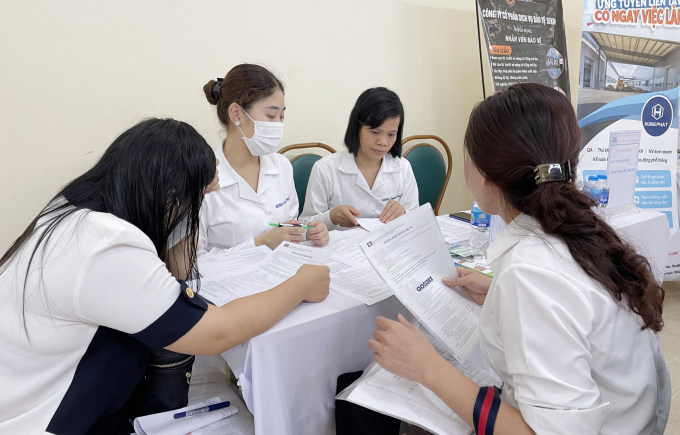 Hien (far R) leaves an employer her personal information at a job fair. Photo by VnExpress/Phan Duong