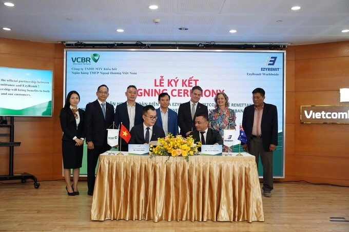 Trinh Hoai Nam (L) and Allan Nguyen (R) the partnership signing ceremony, observed by high ranking representatives behind. Photo courtesy of VCB Remittance