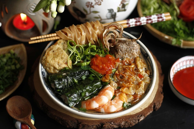 Crab noodle soup is a specialty from Hai Phong. It features a broth made from simmered pork bones and a variety of ingredients such as crab meat, herbs, grilled meatballs, pork rolls, or pork wrapped in betel leaves. The toppings of the crab noodle soup may vary depending on the eatery, but the light red color of the soup remains consistent. Diners can savor it with laksa leaves, perilla leaves, or sliced chili. Photo by Bui Thuy