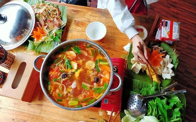 Salmon and sturgeon hotpots are renowned specialties of Sa Pa. This dish includes thinly sliced fish and a hotpot sauce accompanied by local vegetables like squash buds and watercress. The broth plays a crucial role in this dish. A standard hotpot broth should be clear, sweet, sour, and fragrant, with hints of pineapple and other spices. Photo by Hoang Danh Dung