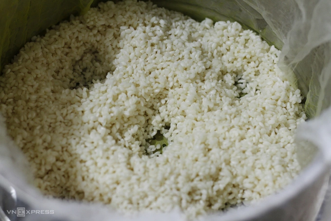 Creating holes in the spread of sticky rice ensures that the rice cooks evenly. Photo by VnExpress/Bui Thuy