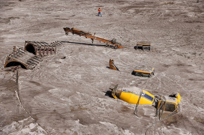 A man walks past construction vehicles covered in debris caused by flash floods after a lake burst in Rangpo, Sikkim state, India, October 8, 2023. Photo by Reuters