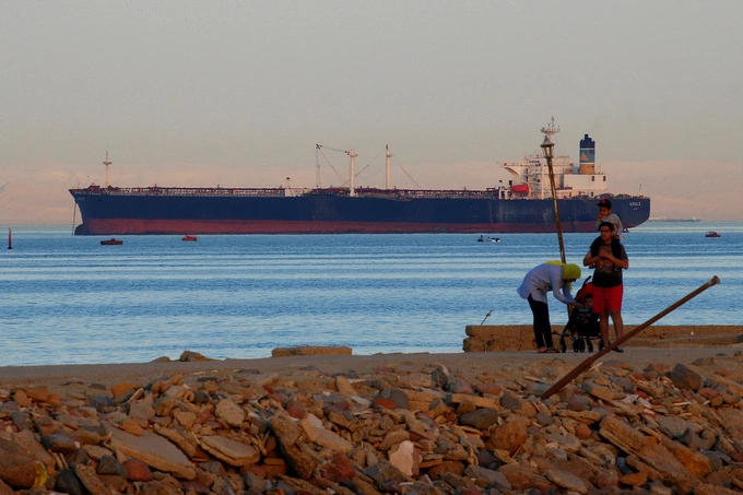 People walk on the beach as a container ship crosses the Gulf of Suez towards the Red Sea before entering the Suez Canal, in El Ain El Sokhna in Suez, east of Cairo, Egypt Apr. 24, 2017. Photo by Reuters