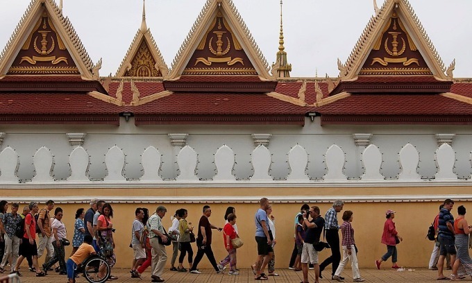 Tourists walk outside the Royal Palace in central Phnom Penh. Photo by Reuters