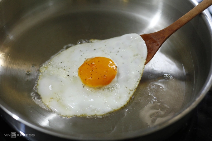 Fry the eggs until the whites are no longer translucent, while ensuring that the yolk remains runny. Photo by VnExpress/Bui Thuy