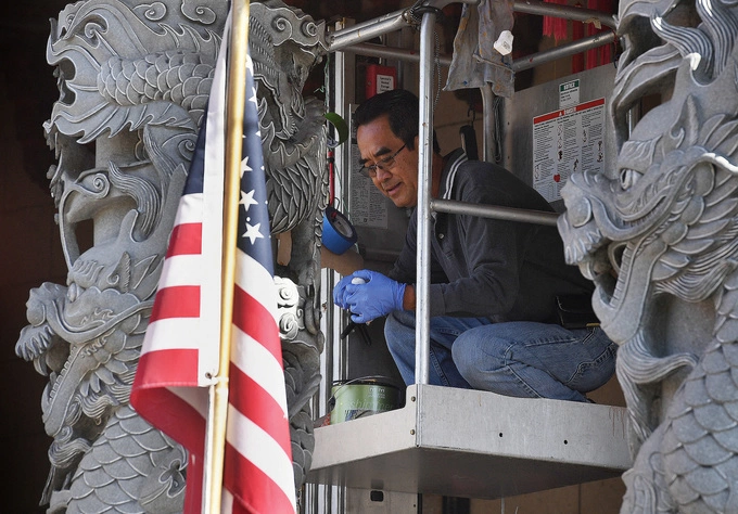 A Vietnamese-American man paints the Vietnamese Thien Hau Temple beside the U.S. flag in Los Angeles, California on Dec. 16, 2018. Photo by AFP
