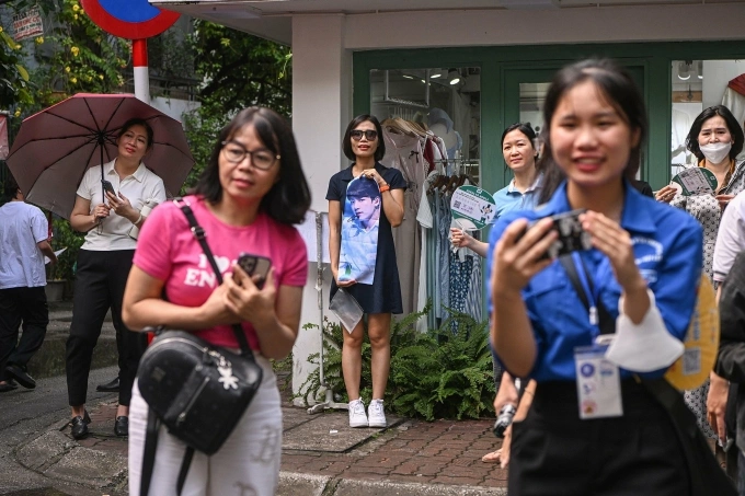 Cách đó 10 km, một phụ huynh cầm theo ảnh thần tượng, đứng trên vỉa hè chờ đợi con bên ngoài điểm thi Trường PTTH Kim Liên, quận Đống Đa, TP Hà Nội. Ảnh:Giang Huy