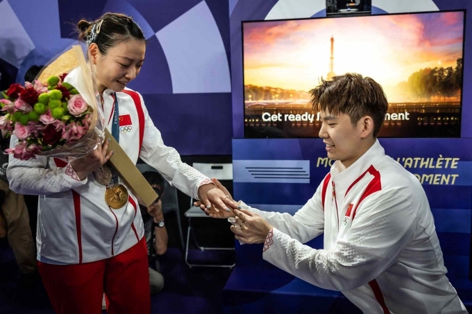 Chinas Liu Yuchen (R) proposes to his partner and gold medallist Huang Ya Qiong after leaving the podium at the mixed doubles badminton medal ceremony during the Paris 2024 Olympic Games at Porte de la Chapelle Arena in Paris on Aug. 2, 2024. Photo by AFP