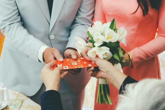 Newlyweds receiving a red envelop from guests. Illustration photo by Pexels