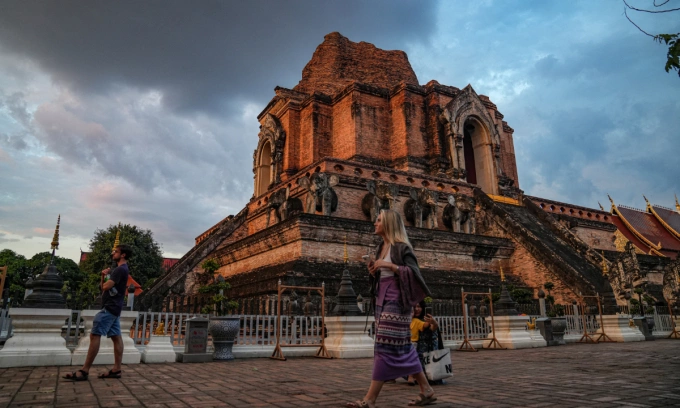 Foreigners walk by a temple in Chiang Mai, Thailand
