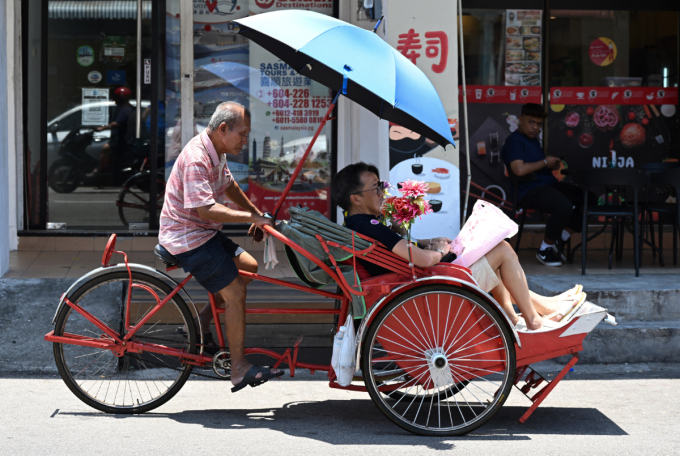 People riding in a trishaw in George Town on Malaysia's Penang island