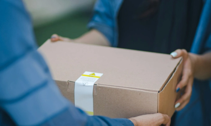 A person delivers a package to a customer. Photo by Unsplash/rosebox