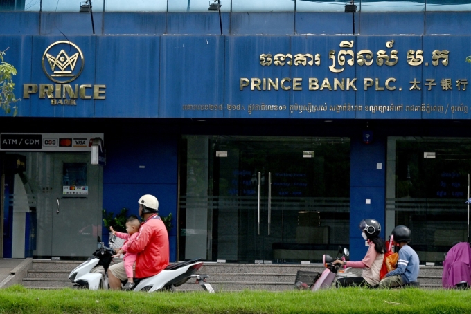 Motorists ride past a branch of the Prince Bank in Phnom Penh on October 15, 2025. Photo by AFP