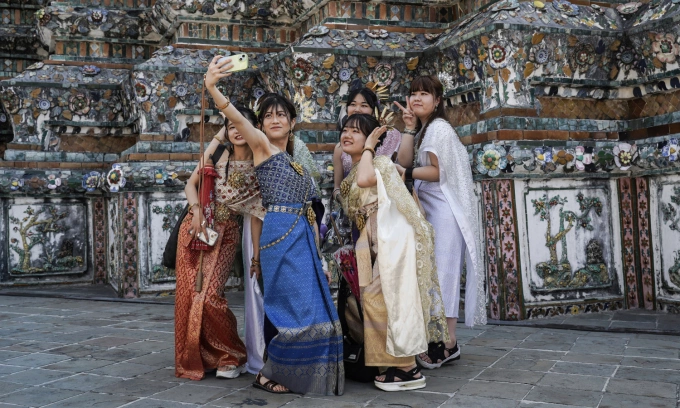 Chinese tourists dressed in Thai traditional costumes rent from a clothing rental shop and take memorial photographs during their visit to Wat Arun or Temple of Dawn in Bangkok, Thailand, on January 13, 2025. Photo by NurPhoto via AFP