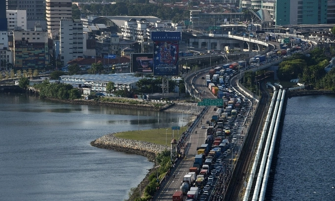 2020 年 3 月 17 日,车辆排着长队从马来西亚南部柔佛州的堤道进入新加坡兀兰检查站。法新社摄