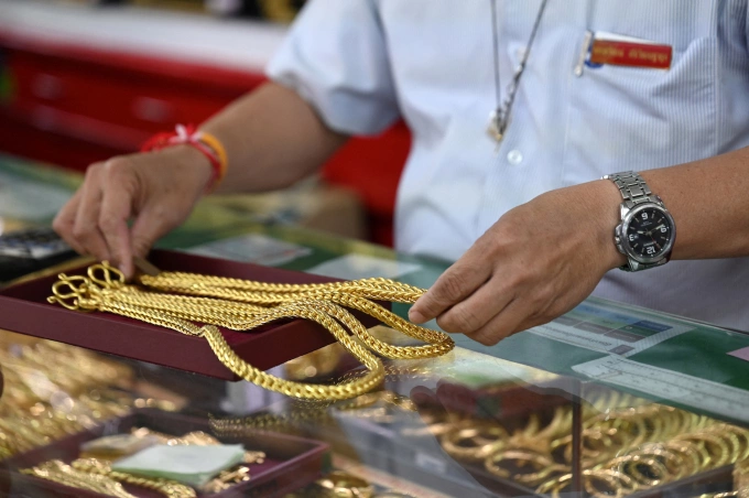 An employee handles gold jewelry for customers at Hua Seng Heng gold traders in Chinatown in Bangkok on April 9, 2025. Photo by AFP