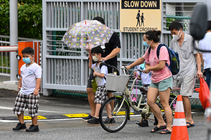 Children walk home with their guardians after school in Singapore. Photo by AFP