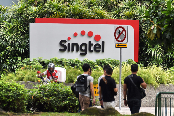 People walk past Singtel logo outside its headquarter building in Singapore on May 12, 2016. Photo by AFP