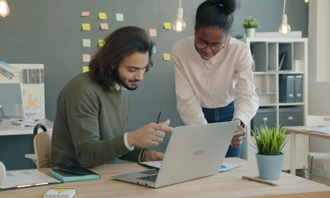 Workers talk in an office. Photo by Unsplash/Vitaly Gariev