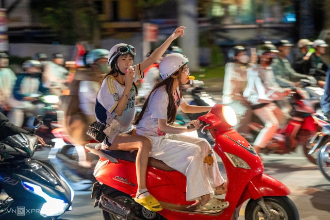 Dos mujeres jóvenes en el desfile en Da Nang. Muchas calles centrales de Da Nang, incluidas 2/9, Nguyen Van Linh y Bach Dang, permanecían abarrotadas a las 2:10 am del sábado con juerguistas ondeando banderas nacionales y cantando victorias de Vietnam. Numerosos jóvenes repartidores y conductores de viajes se unieron a las celebraciones. Se desplegó policía en áreas clave para patrullar el tráfico y abordar casos de conducción rebelde. Foto de Nguyen Dong