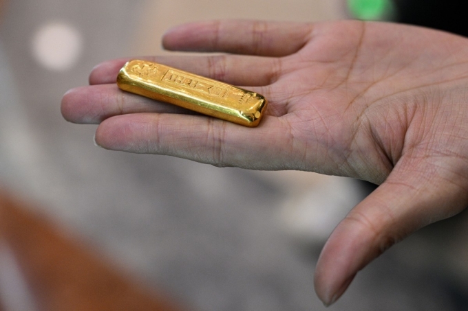 A woman shows a gold bar before selling in a Smart Gold Store Machine placed in a shopping mall in Shanghai on January 29, 2026. Photo by AFP