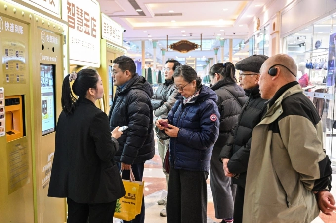 Customers wait to sell their gold jewelry in a Smart Gold Store Machine placed in a shopping in Shanghai on January 29, 2026. Photo by AFP