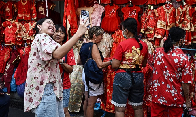 People take pictures with stalls selling red Chinese-style clothes in the Chinatown district of Bangkok on January 29, 2025, on the first day of the Lunar New Year of the Snake. Photo by AFP