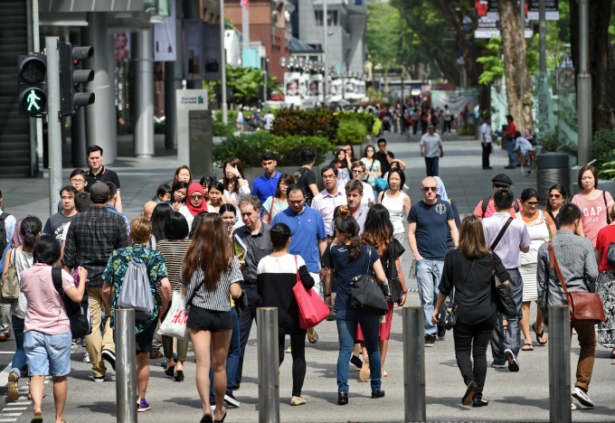 Pedestrians cross a street at the Orchard Road shopping district in Singapore on March 12, 2015. Photo by AFP