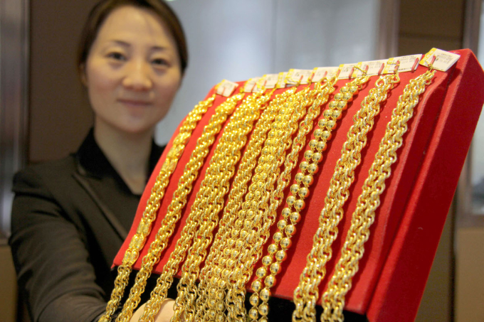 A Chinese employee displays gold necklaces at a jewelry store in Lianyungang city, east Chinas Jiangsu province, 10 December 2014. Photo by Imaginechina via AFP