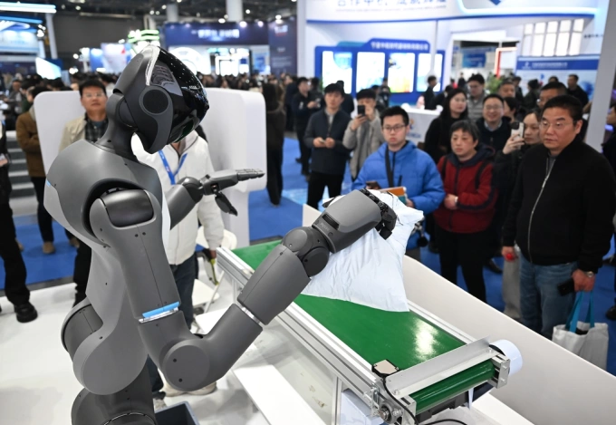 People watch a humanoid robot performs a task at a exhibition in China in March 2026. Photo from X
