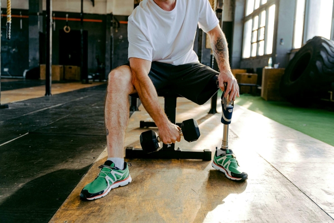 An amputee athlete works out at a gym. Photo by Pexels