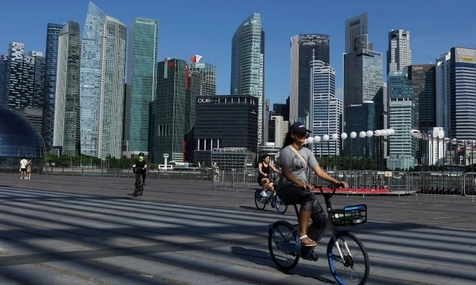Singaporean households can now claim $390 cost-of-living support vouchers 1 People ride bikes past the skyline of the central business district in Singapore, June 13, 2025. Photo by Reuters