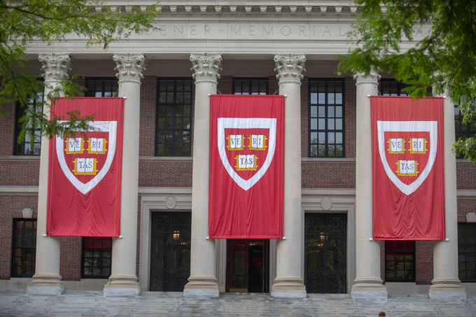 The brick facade with red banners displaying the coat of arms of Harvard University, U.S. Photo courtesy of Harvard